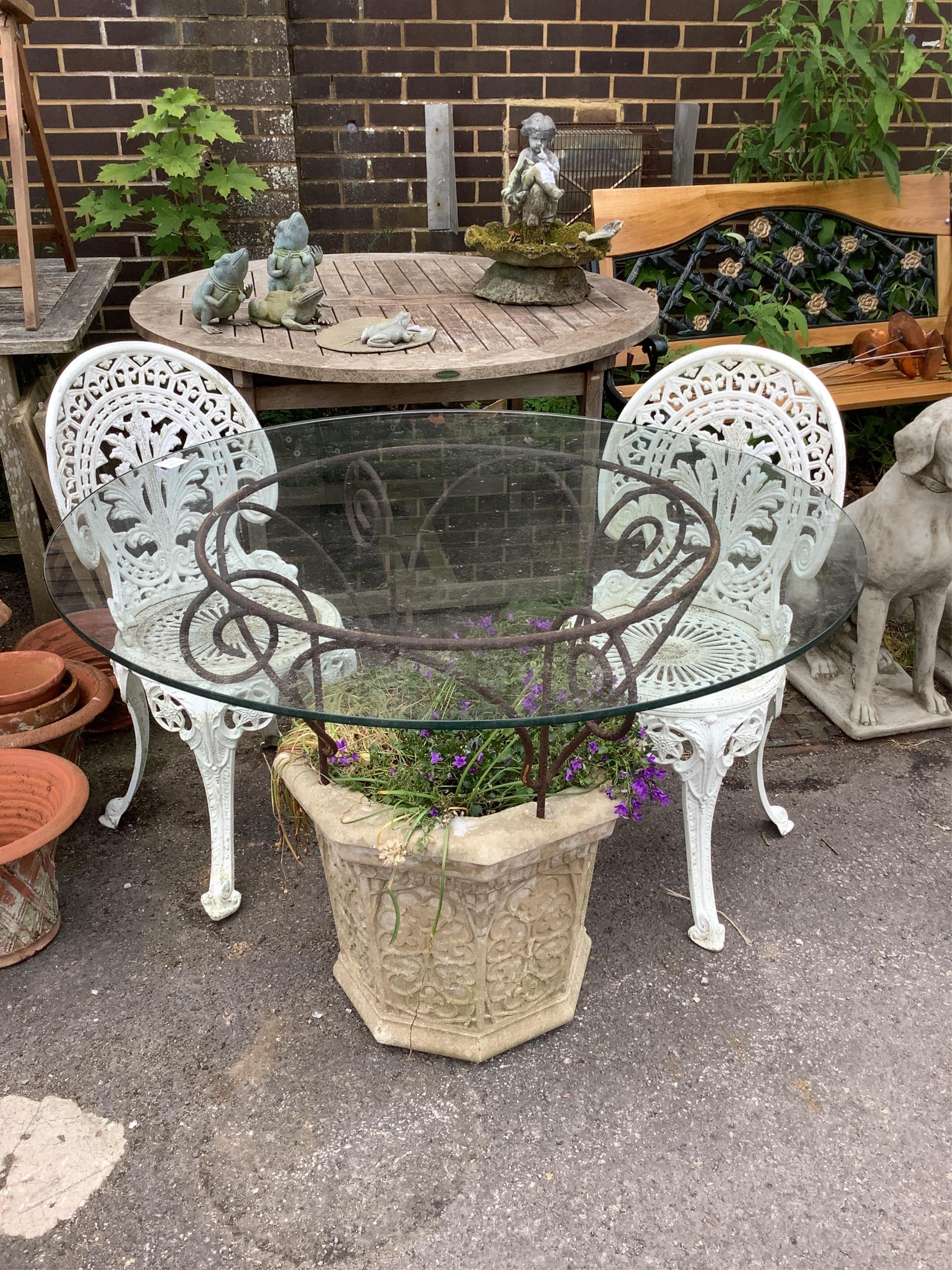 A reconstituted stone and wrought iron glass top garden planter/table, diameter 100cm, height 77cm, together with a pair of aluminium chairs. Condition - good